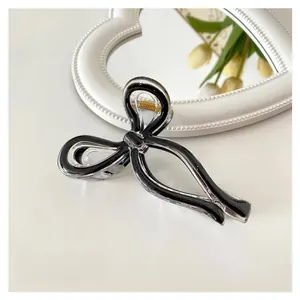 Detail showing an 11cm minimalist black and clear bow hair claw clip with golden spring