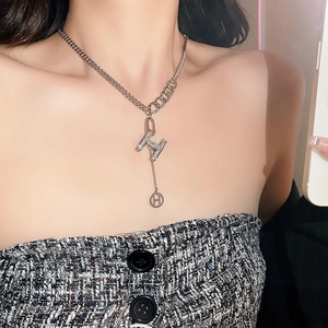 Close-up of silver tone H pendant necklace with crystals on a woman's neck