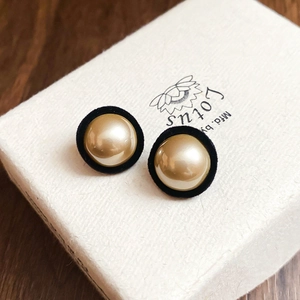 Close-up of vintage round stud earrings with gold faux pearl and black velvet rim