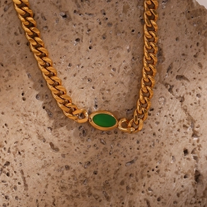 Macro shot of 18K gold plated Cuban chain necklace with oval green gemstone detail