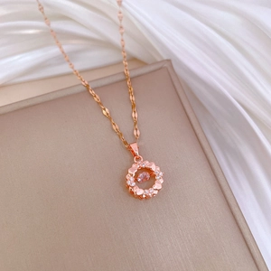 Elegant rose gold circular pendant necklace with pink crystal on beige leather tray