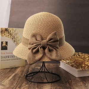 Detail of khaki straw sun hat with large coffee bow on a vintage stand