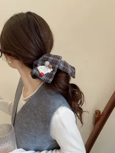 Detail of checkered bow hair scrunchie with vintage label on dark brown fabric