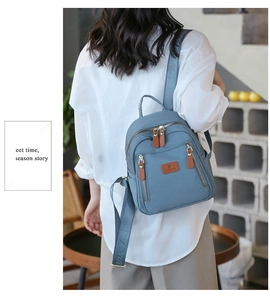 Detail of blue nylon mini backpack with brown leather zipper pulls and logo strap