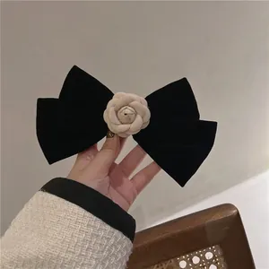 Close-up of black velvet bow hair clip with a delicate beige camellia flower detail