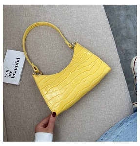 Detailed texture of yellow crocodile pattern faux leather on a vintage shoulder bag