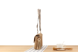 Close-up of khaki hand-woven beach bag featuring a geometric strap and tassel charm detail