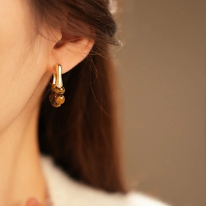 Close-up of vintage gold-plated drop earrings with brown beaded stones on a model