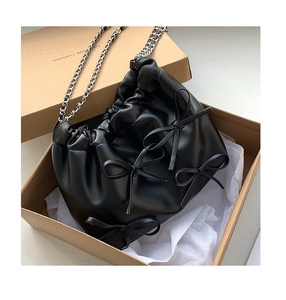 Detailed macro view of black PU leather bag with bows inside an unboxing cardboard box