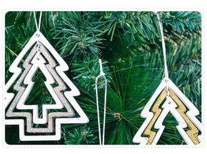Detail of a white wooden Christmas tree ornament with a gold glitter core on pine branches