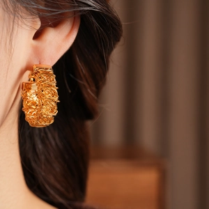 Detail of 24k gold-plated woven texture C-shape hoop earring worn by a model