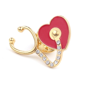 Détail de la broche stéthoscope dorée avec émail cœur rouge et strass brillants