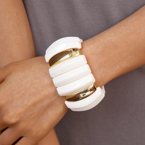 Close-up of white resin and gold metal segments on a stylish wide elastic bracelet