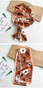 Close-up of orange floral silk scarf with bees and butterflies pattern and white borders