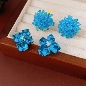Blue glass bead floral and square crystal stud earrings on jewelry display tray