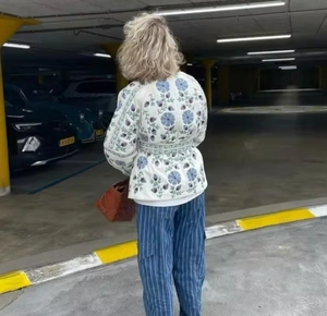 Détail de la broderie florale sur veste blanche à motifs bleus et ceinture nouée