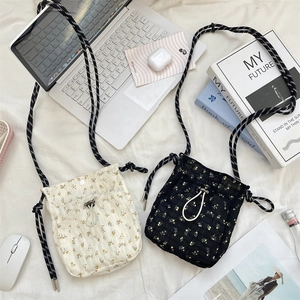Close-up of floral canvas crossbody bags with drawstring closure and woven straps