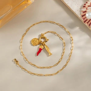 Collier en or avec pendentifs piment, poisson et coquillage sur fond de style plage