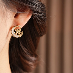 Detail of vintage unicorn and moon earrings with gold finish and white shell inlay