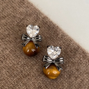 Macro view of heart crystal and tiger eye stone earrings on brown knit background