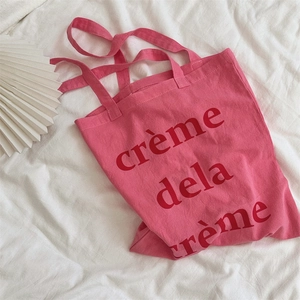 Nahaufnahme der rosa Baumwoll-Tragetasche mit rotem crème de la crème Aufdruck
