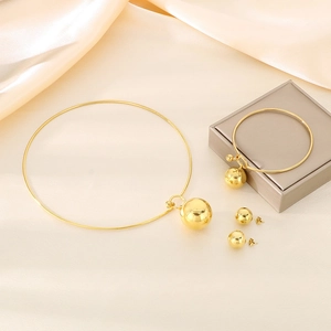 Detailed view of 3-piece gold hollow sphere jewelry set on elegant silk fabric