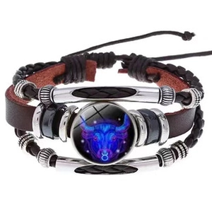 Detail of multi-layer leather bracelet featuring a glowing Taurus zodiac glass charm