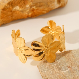 Elegant gold stainless steel open bangle with textured floral design on natural stone