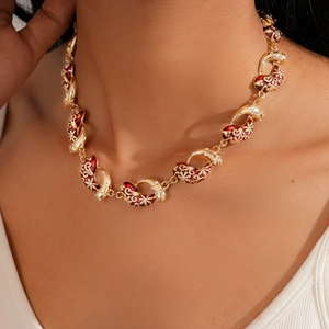 Macro detail of vintage gold sweater chain with red enamel and shimmering zircon accents