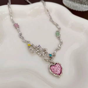 Détails du pendentif cœur serti de cristaux roses sur une chaîne ondulée argentée