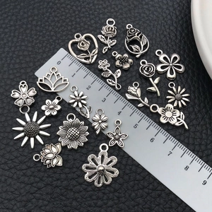 Dettaglio di ciondoli a fiore in argento antico con rose e girasoli e righello per le misure