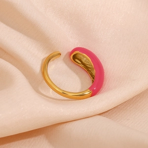 Detail of a gold adjustable ring with pink enamel on soft pink silk fabric background