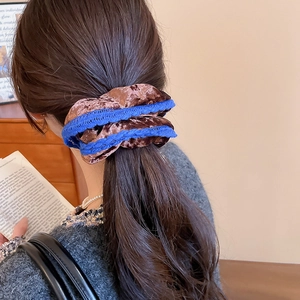 Detail of elegant brown velvet scrunchie with blue lace trim worn on a ponytail