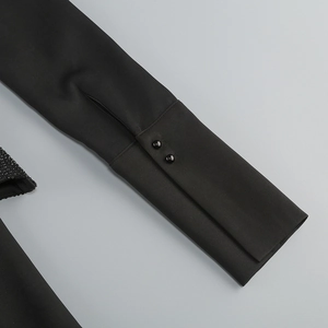 Detail eines eleganten schwarzen Kleidärmels mit zwei Knöpfen und glitzernden Strasssteinen