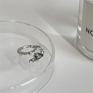Macro detail of adjustable silver ring with irregular texture and teardrop gemstone