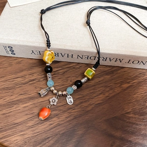 Detail of ethnic ceramic necklace with colorful beads and silver 'Nafu' blessing charm