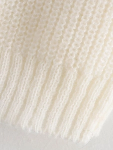 Nahaufnahme eines weißen Strickpullovers mit Rippstruktur und feinen Strickdetails