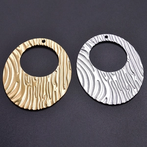 Detailed view of oval water-ripple textured pendants in gold and silver stainless steel