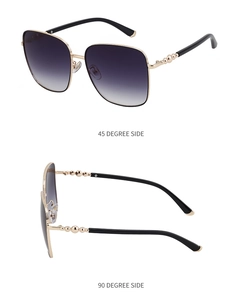 Details einer quadratischen Gold-Sonnenbrille mit dekorativen Perlen am Bügel