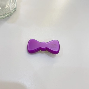 Detail of purple handmade bow hair clip with France engraving on white background