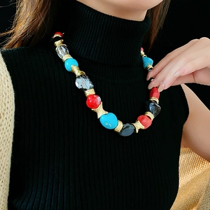 Close-up of vintage beaded necklace with red and blue stones on model in black outfit