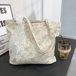 Detailed close-up of a floral canvas tote bag with blue flowers and lace bow detail
