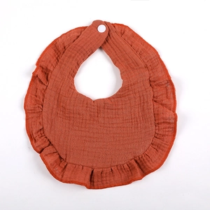 Close-up of burnt orange double layer cotton gauze baby bib with ruffled edge and snap