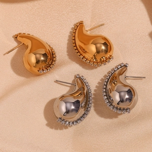 Vue détaillée de boucles d'oreilles goutte or et argent avec zircons sur soie beige