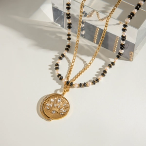 Detail of double-layer necklace with faux pearls, evil eye charm and gold Figaro chain