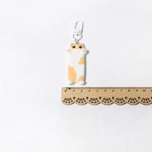 Close-up of cute cat keychain showing 5.5cm size measurement with a wooden ruler