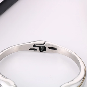 Close-up of engraved STAINLESS STEEL text on the polished silver dolphin bangle