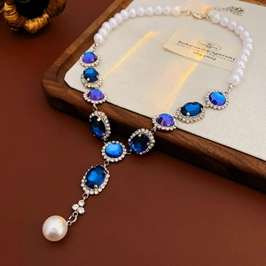 Dettaglio di collana vintage con gemme blu ovali e ciondolo con perla a goccia