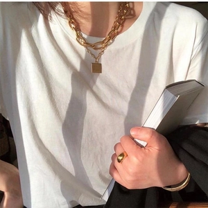 Detail of layered gold link chain necklace and square pendant on female model