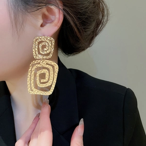 Close-up of gold double-layer square textured earrings on a model with brushed finish